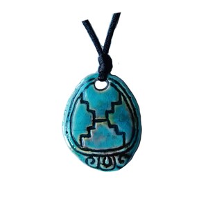May include: A turquoise ceramic pendant with a black cord. The pendant has a unique design with a black outline and a central motif resembling steps or a stylized structure. The pendant is oval-shaped and has a glossy finish.
