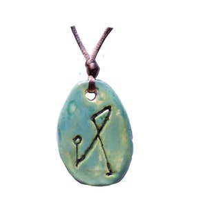 May include: A green ceramic pendant with a brown cord. The pendant has a symbol etched into it.