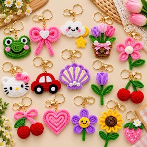 May include: A collection of various macrame keychains featuring colourful designs including a green frog, pink bow, white cloud, potted tulips, pink flower, white cat, red car, purple seashell, purple tulip, red cherries, pink heart, purple flower, sunflower, and strawberry.
