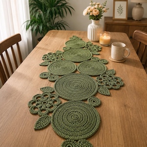 Könnte beinhalten: Ein salbeigrüner Häkel-Tischläufer mit einer Reihe von miteinander verbundenen runden Matten und Blumenmotiven. Das Textilstück besteht aus verschieden großen, massiven Kreisen und durchbrochenen Blumenformen, die alle aus olivfarbenem Garn gefertigt sind.