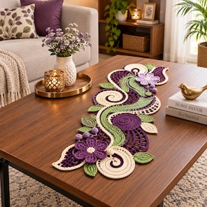 Könnte beinhalten: Ein dekorativer Häkel-Tischläufer mit einem komplizierten Blumen- und Wirbelmuster in den Farben Dunkelviolett, Helllavendel und Salbeigrün. Das Design umfasst gehäkelte Blumen, spiralförmige Kreismotive und Blattformen.