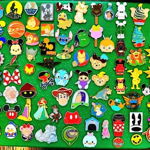 May include: A collection of numerous colorful metal enamel pins featuring various cartoon characters, icons, and shapes arranged on a green rectangular board. The assortment includes diverse designs such as animals, food items, and symbols.