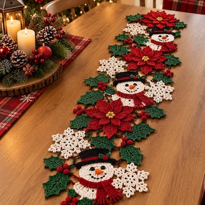 May include: A long, rectangular crochet table runner featuring a repeating pattern of white snowflakes, red poinsettia flowers, green holly leaves, small red berries, and smiling snowmen wearing black top hats and red scarves, all joined together.