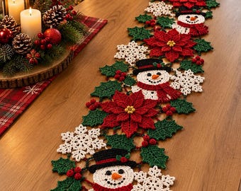 Pode incluir: Um caminho de mesa de crochê longo e retangular com um padrão repetitivo de flocos de neve brancos, flores de poinsétia vermelhas, folhas de azevinho verdes, pequenas bagas vermelhas e bonecos de neve sorridentes com cartolas.