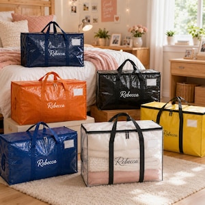 May include: A collection of rectangular storage bags in blue, orange, black, yellow, and clear plastic, each featuring black handles, a zipper closure, a white label window, and the name Rebecca printed in white or black script on the front.