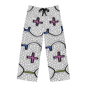 May include: White lounge pants featuring a black puzzle-piece line pattern with scattered pink plus signs, blue accents, and a thin lime green horizontal line. The pants have a black drawstring at the waist and a straight-leg cut with a repeating design.
