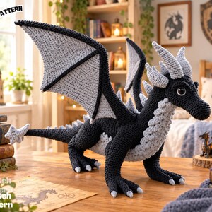 May include: A crochet dragon toy featuring a black body with light gray wings, horns, and underbelly detailing. The creature has large dark eyes, a long tail with a star-shaped tip, and sharp claws. The text PDF PATTERN is visible.
