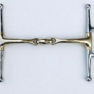 May include: A full-cheek horse bit featuring a silver-coloured metal frame with rounded ends and a gold-coloured metal mouthpiece with a central joint. A small black square tag with the white text GallopGrip is attached to the right side.