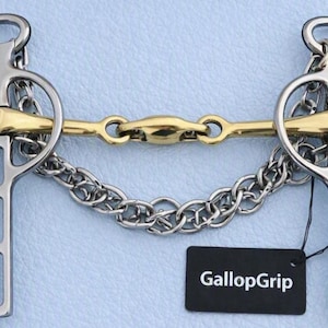 Könnte beinhalten: Ein silber- und goldfarbenes Pferdegebiss aus Metall mit einem gebrochenen Mundstück, zwei Seitenteilen mit kreisförmigen Ringen und einer Kinnkette. Ein schwarzes rechteckiges Etikett an der Kette zeigt den weißen Text GallopGrip in serifenloser Schrift.