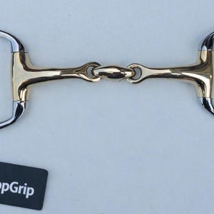 May include: A horse bit featuring a gold-coloured metal mouthpiece with a central lozenge link and silver-coloured stainless steel D-rings. A black rectangular tag with the white text GallopGrip is attached to the left ring by a black string.