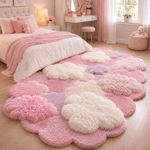 May include: A plush, shaggy area rug featuring a repeating cloud-like pattern in shades of soft pink, cream, and light purple. The rug has a thick, textured pile and a rounded, organic shape that covers the floor space in front of a bed.