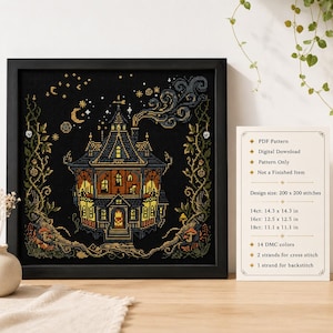May include: A framed cross-stitch embroidery featuring a dark, multi-story house with glowing yellow windows, surrounded by swirling vines, stars, and a crescent moon on a black background. A white card lists pattern details including 200x200 stitches.
