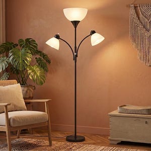May include: A black metal floor lamp featuring a central upward-facing frosted glass shade and two adjustable side arms, each equipped with a smaller matching frosted glass shade, all emitting a warm light from a circular base.