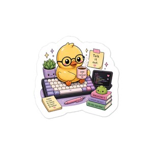 Op de afbeelding: Een stickerillustratie van een gele eend met een zwarte bril, zittend op een paars en zwart mechanisch toetsenbord. De eend houdt een mok vast met de tekst CODE + CAFFEINE. Daarnaast staan een vetplant, een roze pen, een monitor en boeken.