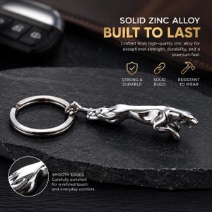 May include: A silver-toned metal keychain featuring a leaping jaguar figure attached to a circular split ring. The text reads: SOLID ZINC ALLOY BUILT TO LAST, STRONG & DURABLE, SOLID BUILD, RESISTANT TO WEAR, and SMOOTH EDGES Carefully polished.