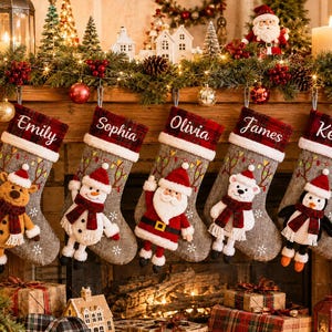 Op de afbeelding: Vijf grijze kerstsokken met rood-zwart geruite boorden, gepersonaliseerd met de namen Emily, Sophia, Olivia, James en Kevin. Elke sok is voorzien van een pluche figuur: een rendier, sneeuwman, kerstman, ijsbeer en pinguïn.