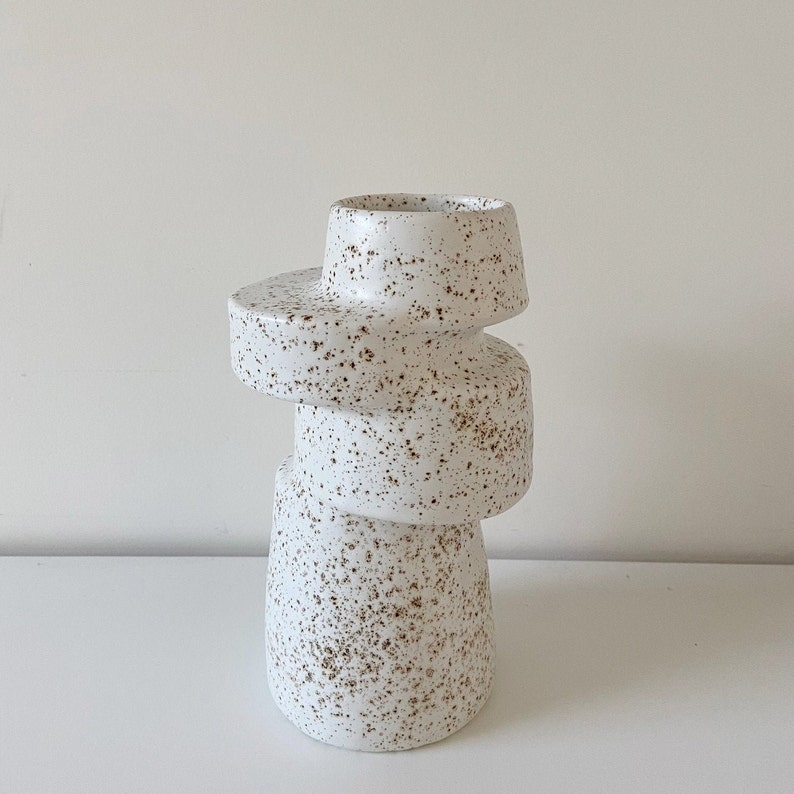 A-symmetrical vase in offwhite with brown speckles. This unique interior accessory is handmade from a mould. The mould is made from a unique vase I made on a potterswheel. This shape is perfect match to a Scandinavian and Japandi style interior.