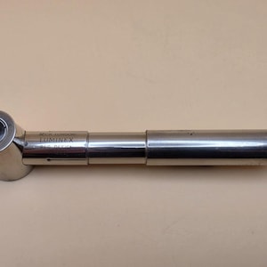 May include: A silver-coloured metal Beck London Luminex magnifying tool with a cylindrical handle and a circular lens head. The device features the text X10 on the lens rim and Beck London Luminex Reg Design engraved on the central barrel section.