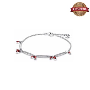 May include: A silver chain bracelet featuring multiple baguette-cut red stones set in silver bars. The bracelet includes a lobster claw clasp and a small star-shaped charm at the end of the chain, providing a delicate and refined appearance.