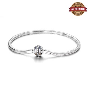 Könnte beinhalten: Ein silbernes Schlangenkettenarmband mit einem kugelförmigen Verschluss, in den das Wort FOREVER eingraviert ist. Der Verschluss ist mit kleinen, bunten Steinen in Blau, Orange und Transparent auf einer polierten Metalloberfläche mit Herzmotiven verziert.
