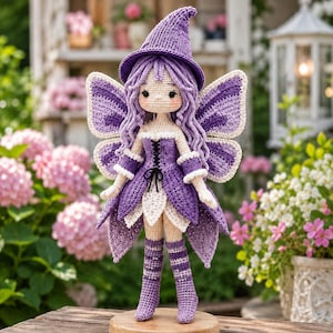 Puede incluir: Una muñeca de ganchillo con un sombrero puntiagudo morado, largo cabello ondulado morado y grandes alas moradas y blancas. La muñeca viste un vestido morado con un corpiño negro con cordones, ribete de volantes blancos y calcetines altos a rayas moradas.