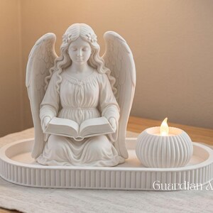 Pode incluir: Uma estatueta de anjo branco fosco com asas, segurando um livro aberto, posicionada numa bandeja oval estriada ao lado de um pequeno suporte de vela branco redondo e canelado com uma chama. O texto "Guardian Angel Kit" é visível no canto inferior direito.