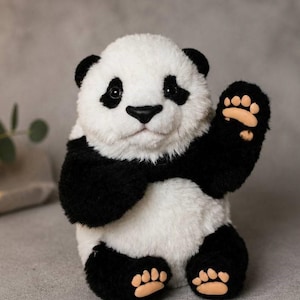 May include: A plush panda toy with white and black fur, featuring a round head, dark eyes, a black nose, and raised front paws. The panda has light tan paw pads on its feet and one raised hand, showcasing detailed toe and palm markings.