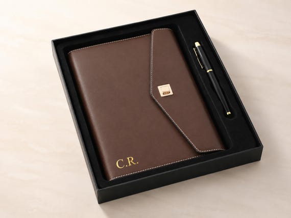A refillable monogrammed leather loose-leaf planner with a pen loop — genuinely functional craft that gets better with age.