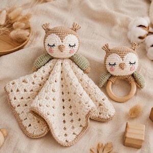 May include: A crochet owl security blanket with a cream-colored square base and a matching crochet owl rattle featuring a wooden ring. Both items have tan and white yarn, embroidered closed eyes, and small pink cheeks with green wing accents.