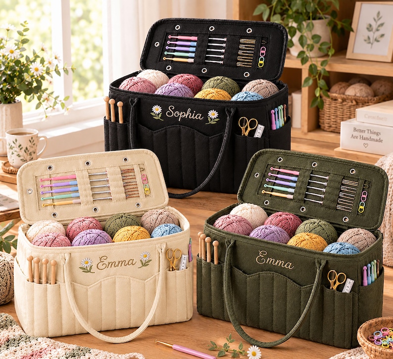 May include: Three rectangular fabric yarn storage bags in black, cream, and olive green. Each bag features an embroidered name, daisy accents, multiple exterior pockets for crochet hooks and scissors, and an interior lid organizer for needles.