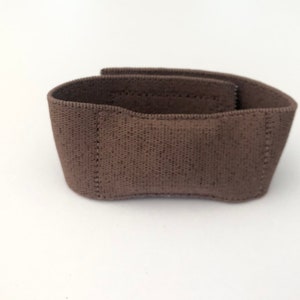 May include: A brown fabric wrist support with a textured surface.