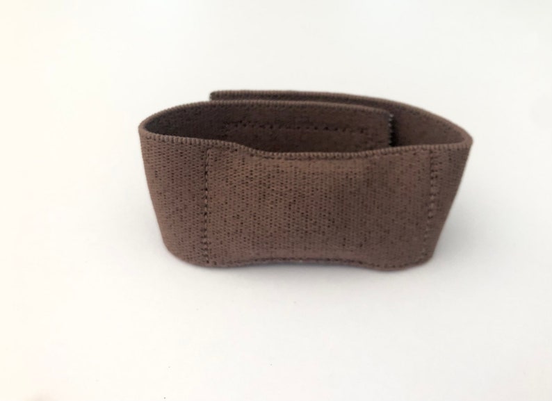 May include: A brown fabric wrist support with a textured surface.