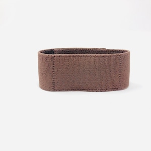 May include: A brown fabric resistance band for exercise.