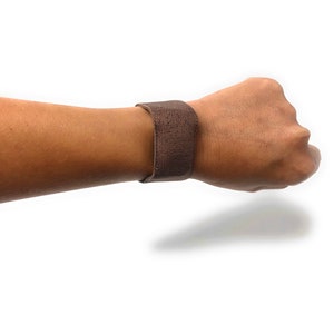 May include: A brown elastic wristband with a textured surface.