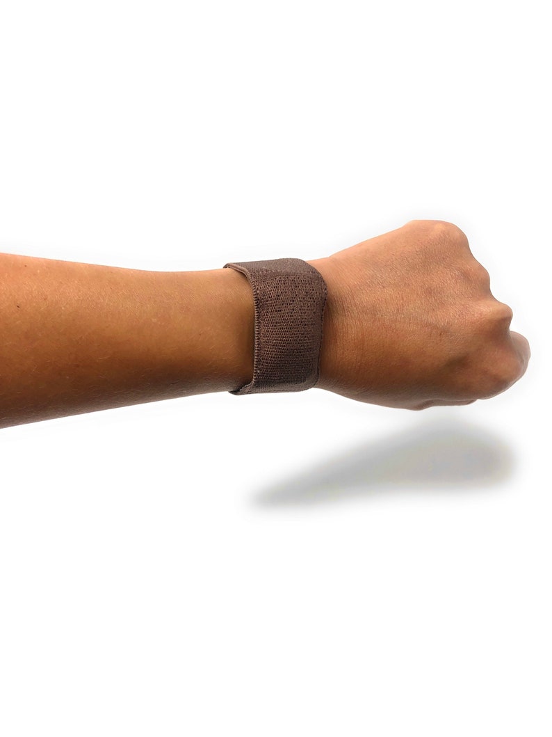 May include: A brown elastic wristband with a textured surface.
