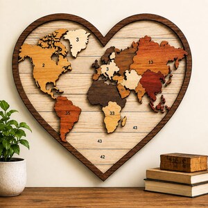 May include: A heart-shaped wooden wall art piece featuring a world map made of layered wood pieces in various brown tones. The map is set against a light wood-plank background. Several landmasses and areas are marked with black numbers including 2, 3, 13, 33, 35, 42, and 43.