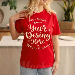 May include: A bright red short-sleeved t-shirt featuring cream-colored text that reads Real Model Yuor Desing Here Dream Mockup, accented with small star graphics arranged in a circular pattern across the center of the chest area.
