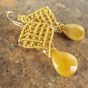 Peut inclure: Une paire de boucles d'oreilles en or avec un motif nou&eacute; d&eacute;licat et des pierres ambr&eacute;es en forme de larme.