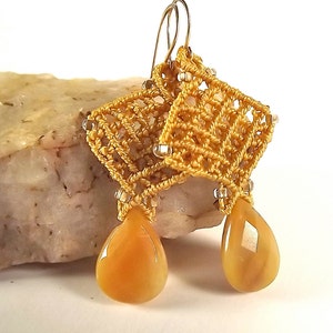 Peut inclure: Une paire de boucles d'oreilles dor&eacute;es avec un d&eacute;licat motif crochet&eacute; et des pierres ambr&eacute;es en forme de larme.