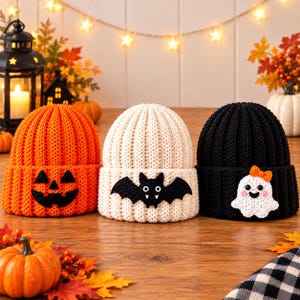 Può includere: Tre berretti in maglia a coste con motivi di Halloween. Il berretto arancione ha una faccia da zucca, quello color crema mostra un pipistrello nero con zanne bianche e quello nero presenta un fantasma bianco con un piccolo fiocco arancione.