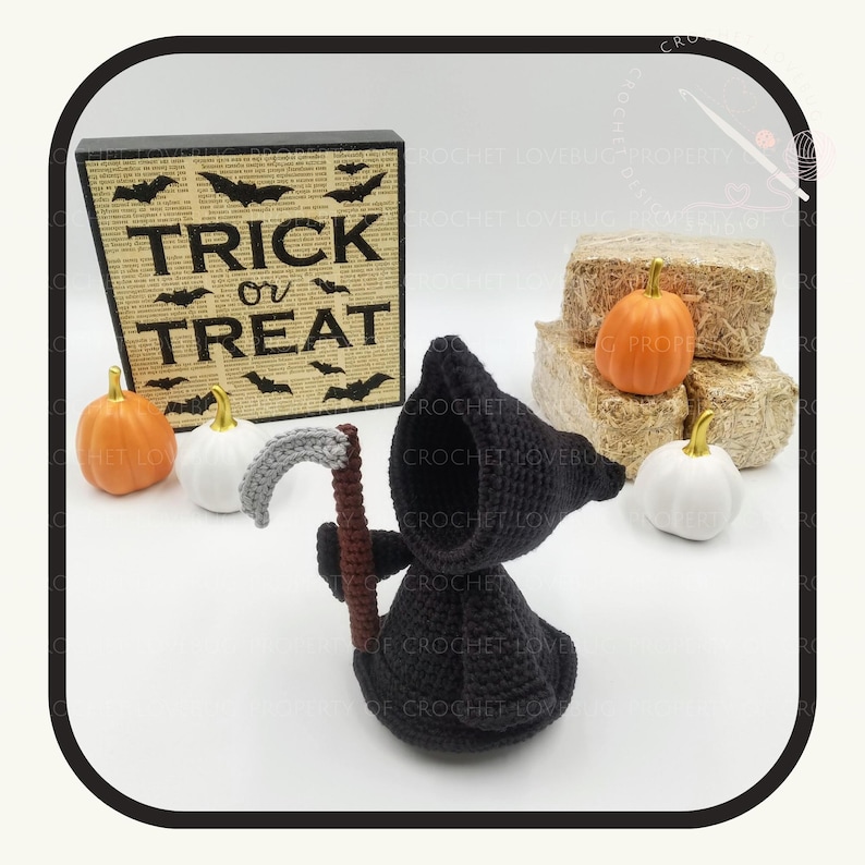 May include: A black crochet Grim Reaper figure with a scythe, next to a sign that says "TRICK OR TREAT" with bat silhouettes. There are also orange and white pumpkins, and hay bales. Halloween-themed decor.