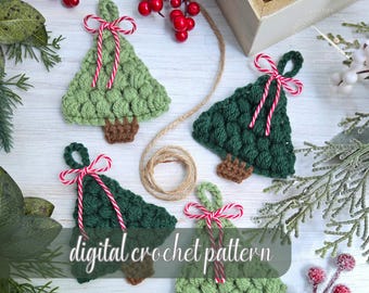 May include: Crocheted Christmas tree ornaments in shades of green, with brown trunks and red and white striped bows. The ornaments are arranged on a white surface with decorative greenery and berries. The text "digital crochet pattern" is visible.