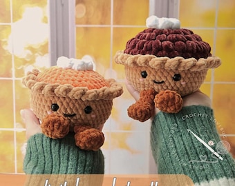 May include: Two plush crochet pies with smiling faces, black eyes, and pink cheeks. One pie is orange with a tan crust, and the other is dark brown with a tan crust. Both have white dollops on top and small brown feet. Text reads digital crochet pattern.