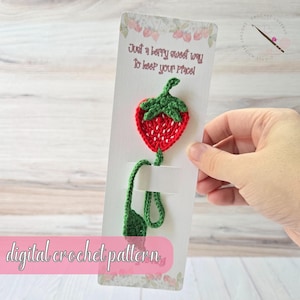 May include: A crochet strawberry bookmark with a green stem and leaves, attached to a card. The card has text that reads "Just a berry sweet way to keep your place!" and "digital crochet pattern". The strawberry is red with white detailing.