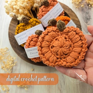 Puede incluir: Primer plano de esponjas faciales con forma de calabaza de ganchillo naranja con tallos marrones. Las esponjas están hechas a mano y etiquetadas como "Facial Scrubbies". La imagen también incluye el texto "digital crochet pattern".