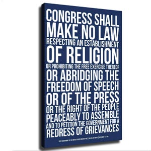 Può includere: Un quadro rettangolare su tela blu navy con il testo bianco del Primo Emendamento della Costituzione degli Stati Uniti. La stampa riporta il testo completo che inizia con Congress shall make no law e termina con redress of grievances.