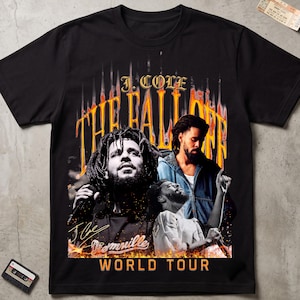 May include: A black short-sleeve t-shirt featuring a graphic print of J. Cole. The design includes the text J. COLE, THE FALL OFF, and WORLD TOUR in orange and yellow, with three photographic images of the artist and a signature overlay.