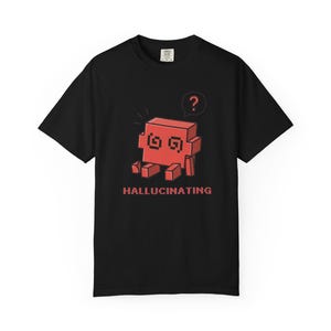 May include: A black short-sleeve t-shirt featuring a red pixelated block character with spiral eyes and a question mark speech bubble above its head. The word HALLUCINATING is printed in red pixelated text below the character on the front.