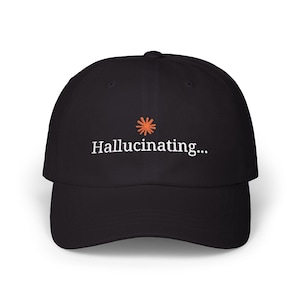 May include: A black baseball cap featuring an embroidered orange starburst icon above the white text "Hallucinating..." centered on the front panel. The cap has a curved brim and a structured crown with a button at the top center.