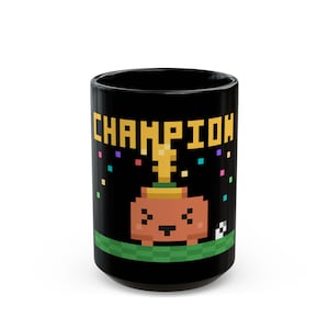 May include: A black ceramic mug featuring a pixel art graphic of a brown creature wearing a gold trophy on its head. The text CHAMPION is printed in yellow pixelated letters above the creature, with colorful confetti squares scattered around.